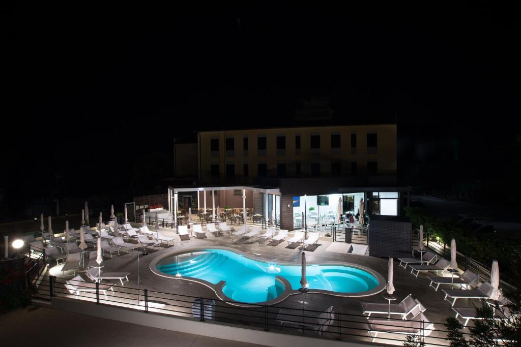 Hotel Ristorante Dante في تورجانو: مسبح في الليل مع كراسي ومبنى