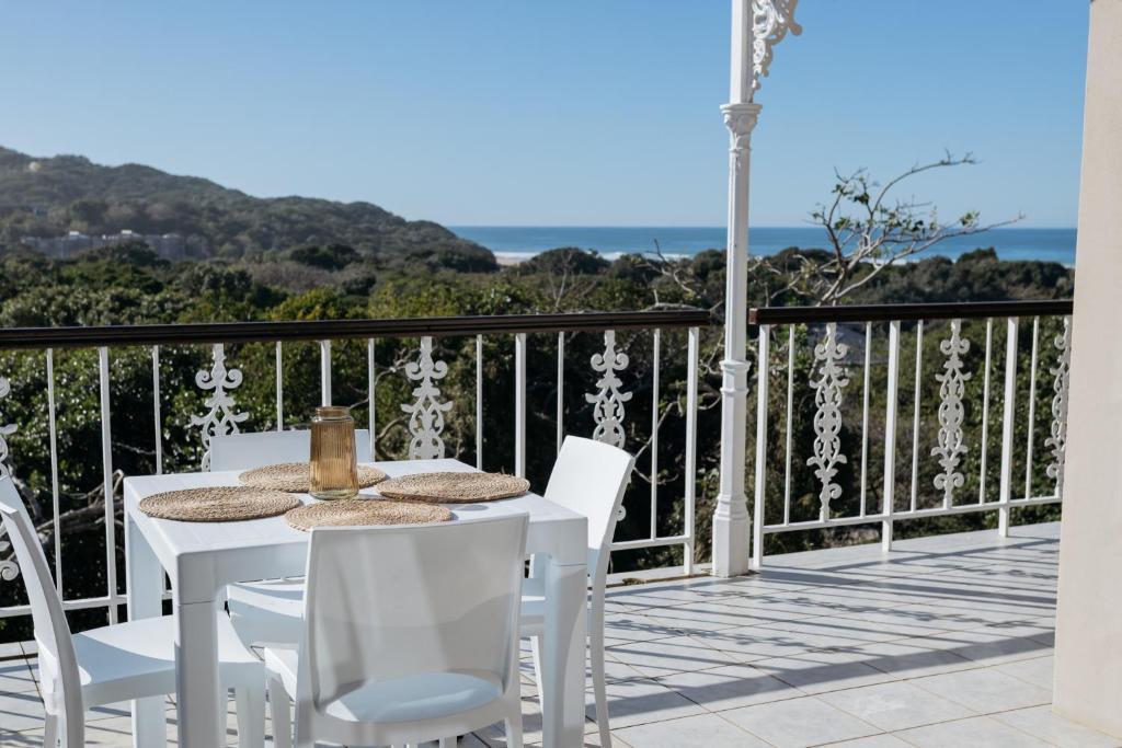a white table and chairs on a balcony with the ocean at Nahoon Beach Villas Self Catering Apartments in East London