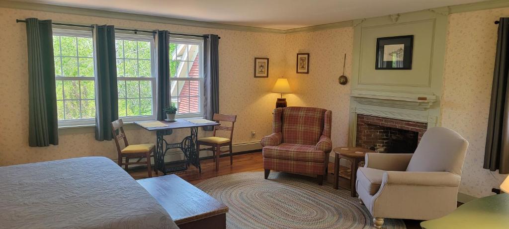 a bedroom with a bed and a living room with a fireplace at Hawks House Inn in Walpole