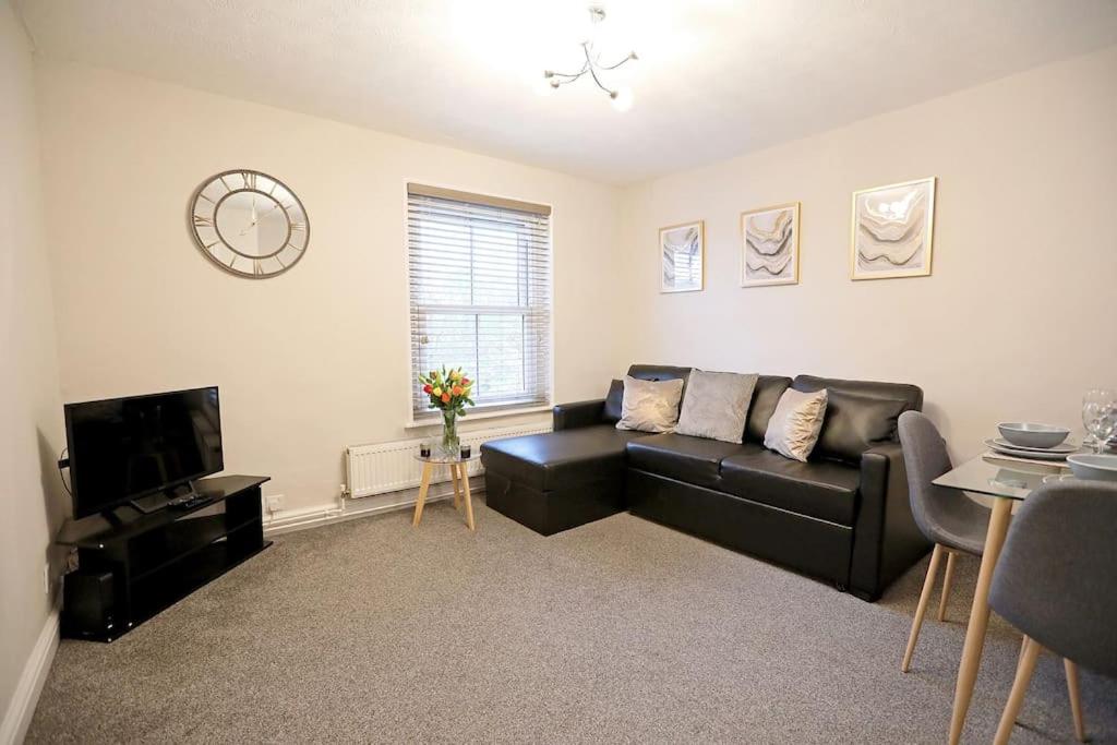 a living room with a black couch and a tv at The Rosary Rest in Norwich