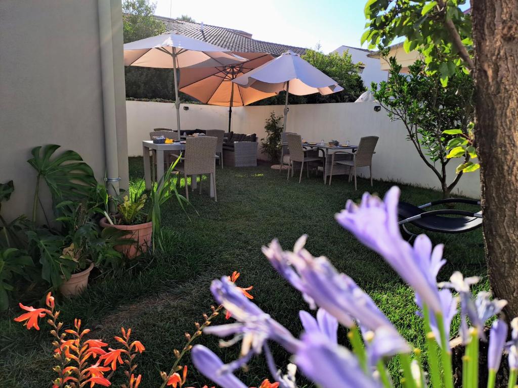 un jardín con mesas, sombrillas y flores púrpuras en Costeras, en Cabras