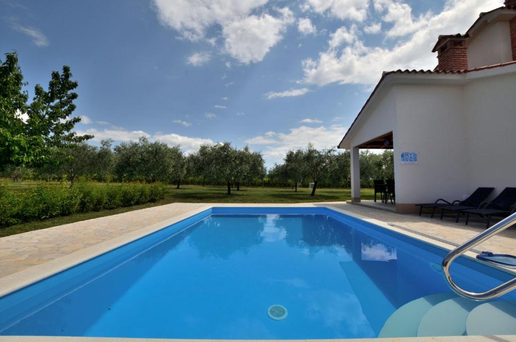 a swimming pool with blue water in front of a house at House Danci in Lašći