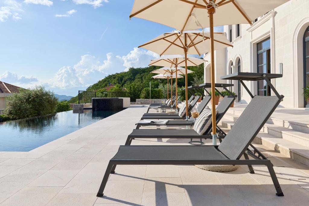 a row of lounge chairs with umbrellas next to a pool at Eterno Villas in Budva