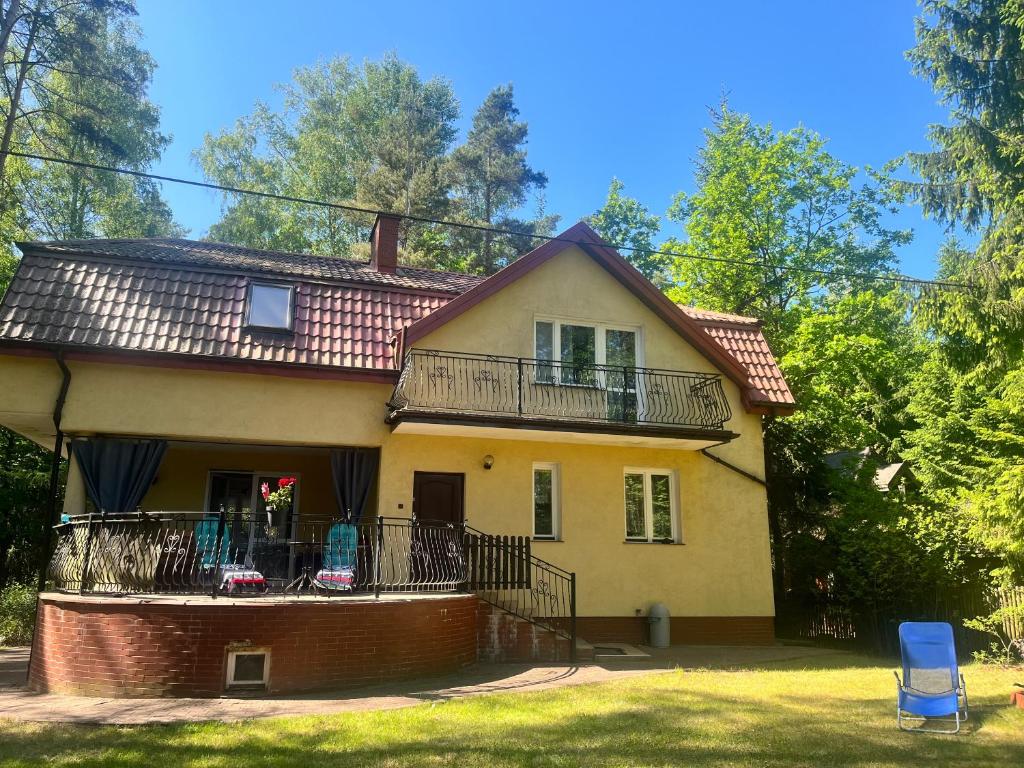 a yellow house with a balcony and a yard at Mazury- dom wakacyjny in Pisz