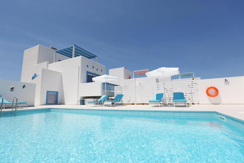 a swimming pool with chairs and a building at Xenos Villa 5 with a Private pool near the sea in Tigaki