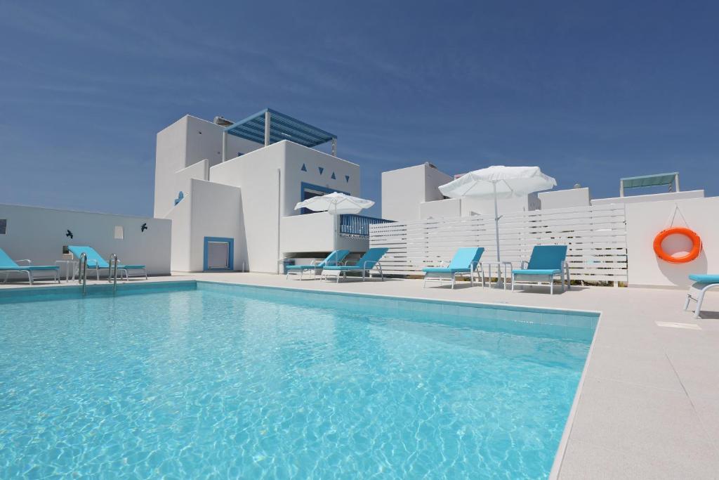 une piscine avec des chaises bleues et un bâtiment dans l'établissement Xenos Villa 5 with a Private pool near the sea, à Tigaki