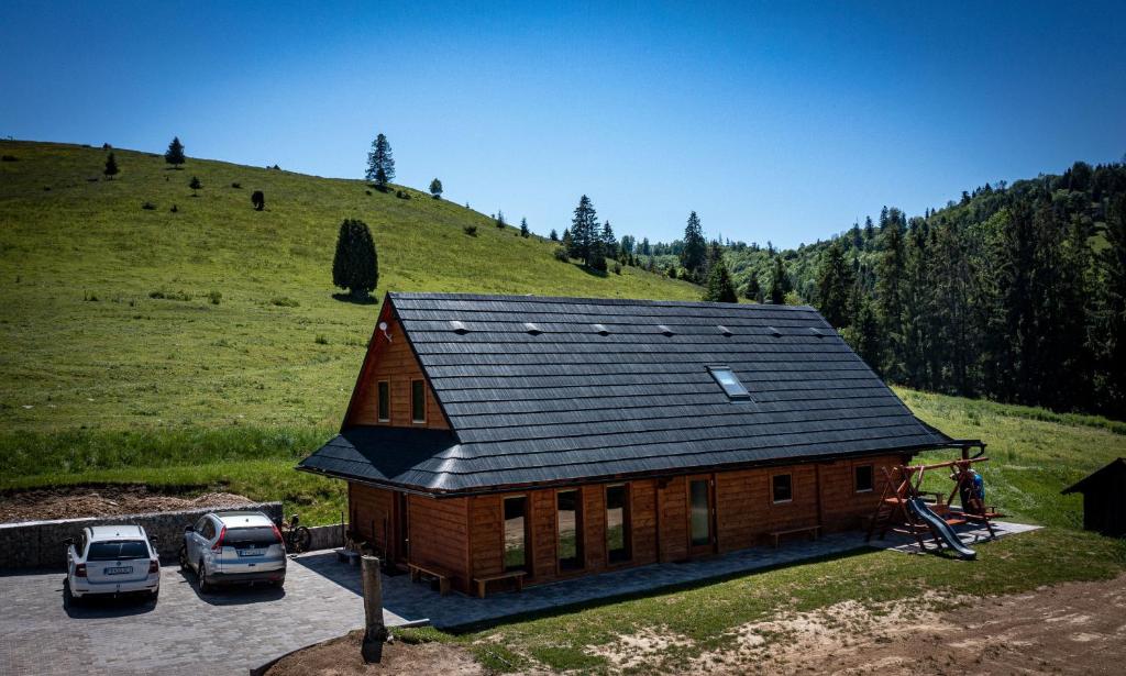 una gran casa de madera con coches aparcados en un aparcamiento en Chata Planina en Michalová