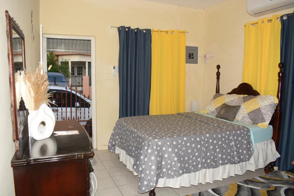 - une chambre dotée d'un lit avec des rideaux bleus et jaunes dans l'établissement Cozy Oasis Studio, à Portmore