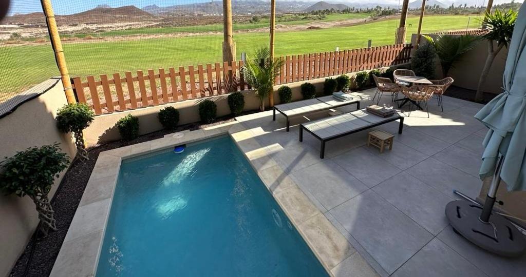 a swimming pool on a patio with a table and a bench at Golf Tenerife South xx Our Top Pick xx Top Rated vacation rental xx Wheel accesible showers and accomodation xx Free WiFi xx Heated private Pool xx Two terraces 30 m2 x60 m2 xx Free parking xx Mountain view xx Flatscreen 65 inch xx in San Miguel de Abona
