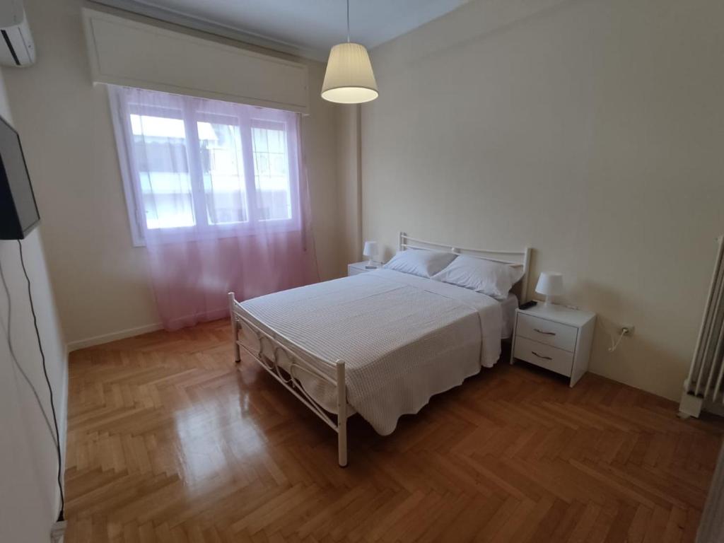 um quarto com uma cama branca e uma janela em Cozy flat em Atenas