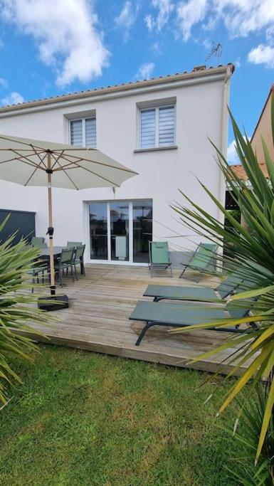 une terrasse en bois avec des bancs et un parasol dans l'établissement Entre terre et mer, à Saint-Brévin-les-Pins