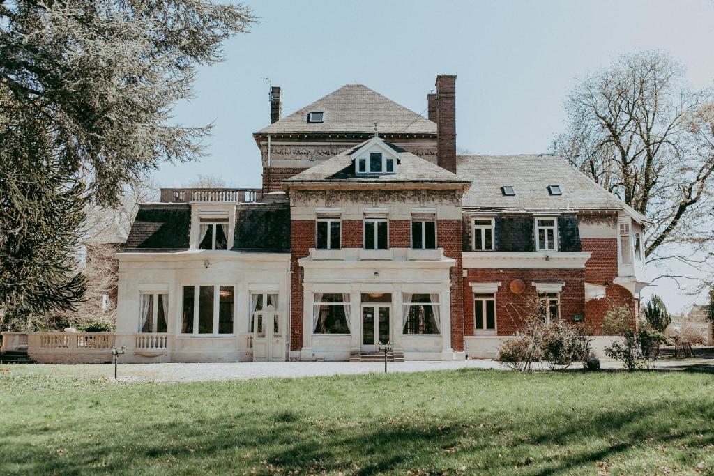 a large brick house with a large front yard at Manoir Les Cèdres in Corbehem