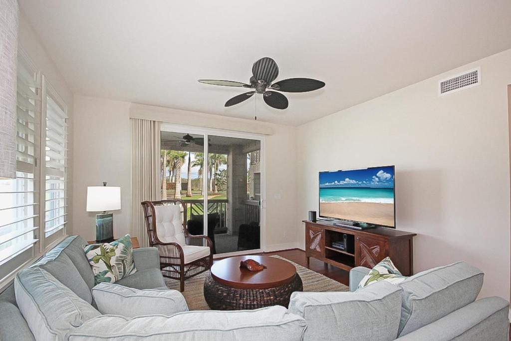 Una sala de estar con dos sofás y un televisor de pantalla plana. en Pili Mai 15A, en Koloa