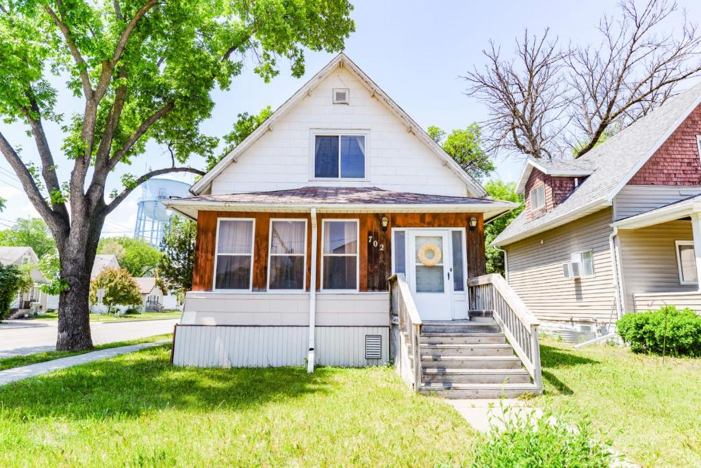 une maison blanche avec une terrasse couverte et des escaliers dans l'établissement Unique Two Story with a Vintage Flare, à Fargo