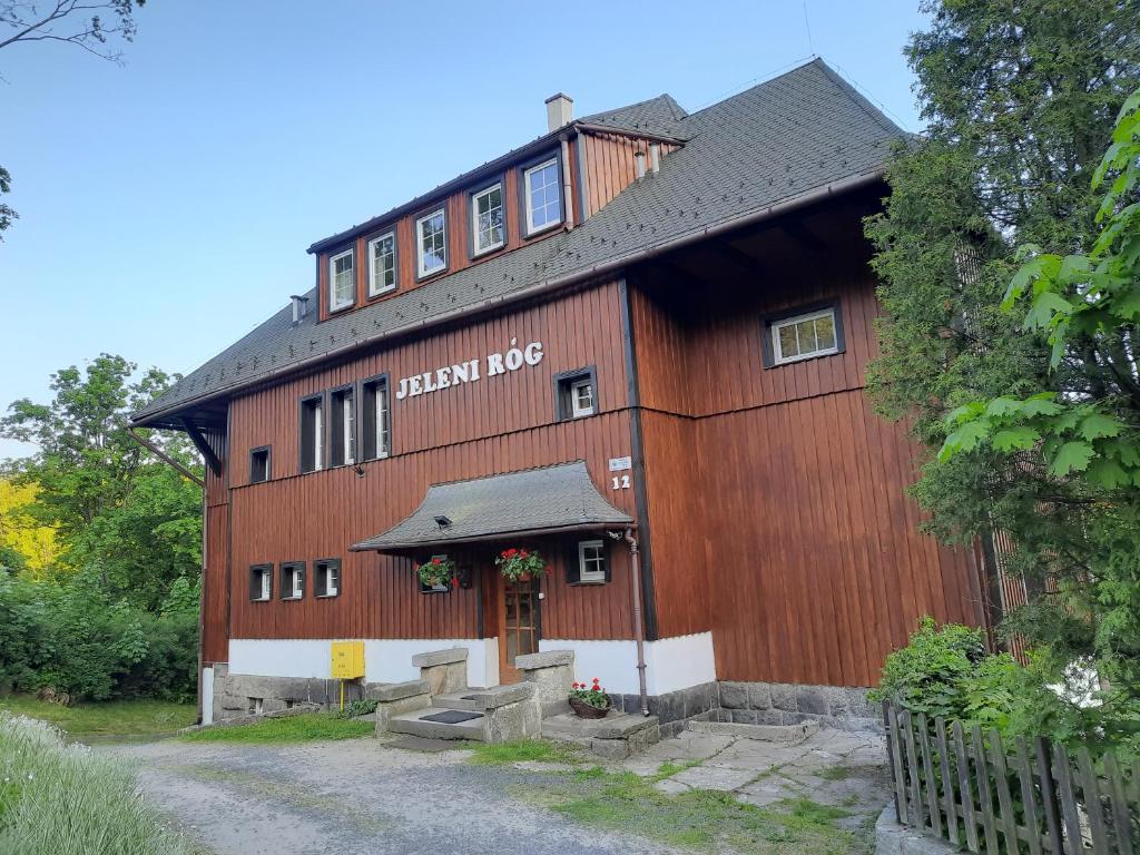 un grand bâtiment en bois avec un panneau. dans l'établissement Pensjonat Jeleni Róg, à Szklarska Poręba