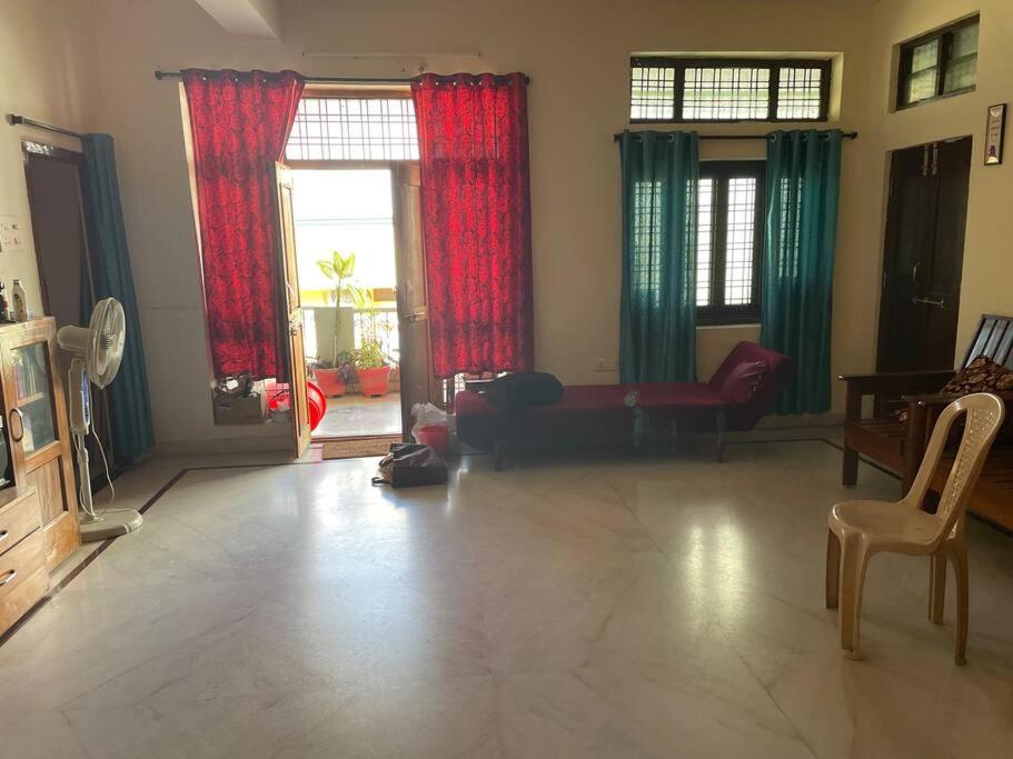 a living room with a couch and red curtains at City Style Cottage in Surūrnagar