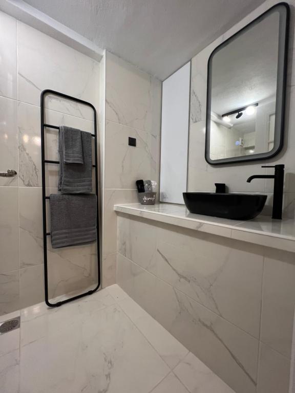 ein Bad mit einem schwarzen Waschbecken und einem Spiegel in der Unterkunft Riviera-MelRod-Athens in Athen