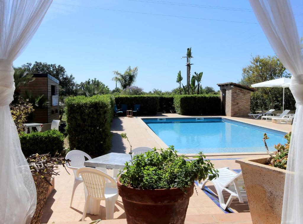 un patio con piscina, sillas y mesa en B&B Il Mandorleto Avola, en Avola