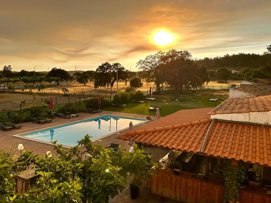 vista para uma piscina num resort com o pôr-do-sol em Hotel Boavista - Vintage House em Monfortinho