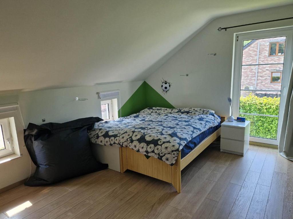 ein Schlafzimmer mit einem Bett und einem großen Fenster in der Unterkunft Chambre proche du circuit in Spa