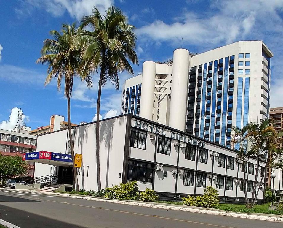 a large white building with palm trees in front of it at Hotel Diplomat in Brasília