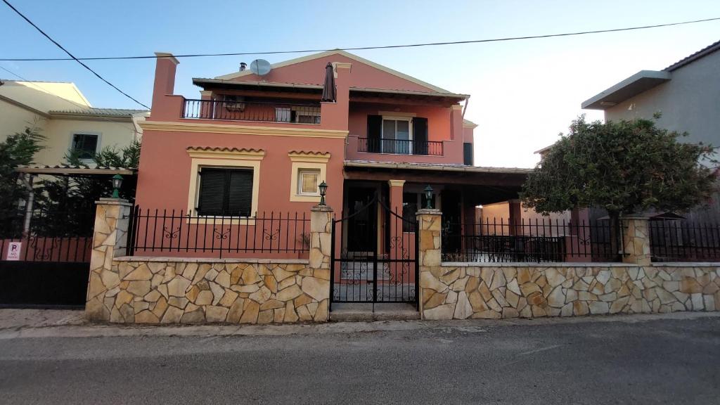 una casa rosa con una recinzione in pietra di Kallistimon House a Ipsos