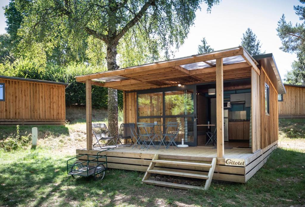 une petite maison avec une terrasse dans la cour dans l'établissement Huttopia Lac de la Siauve, à Lanobre