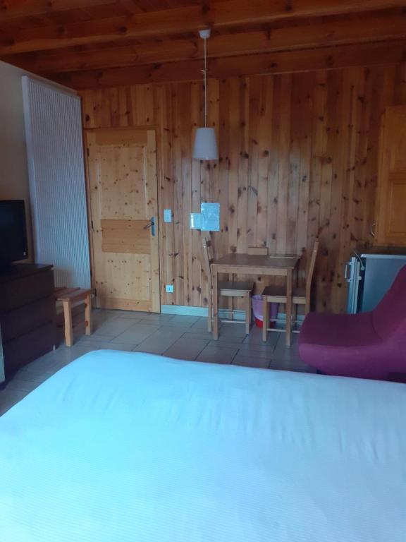 Cette chambre dispose d'une table, de chaises et d'un mur en bois. dans l'établissement Hotel restaurant la terrasse du mont bar hotel leydier, à Allègre