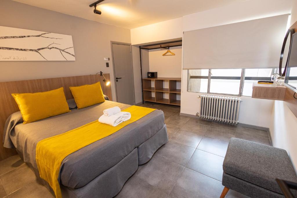 ein Schlafzimmer mit einem großen Bett mit gelben Kissen in der Unterkunft HOTEL CONCEPT BARILOCHE in San Carlos de Bariloche