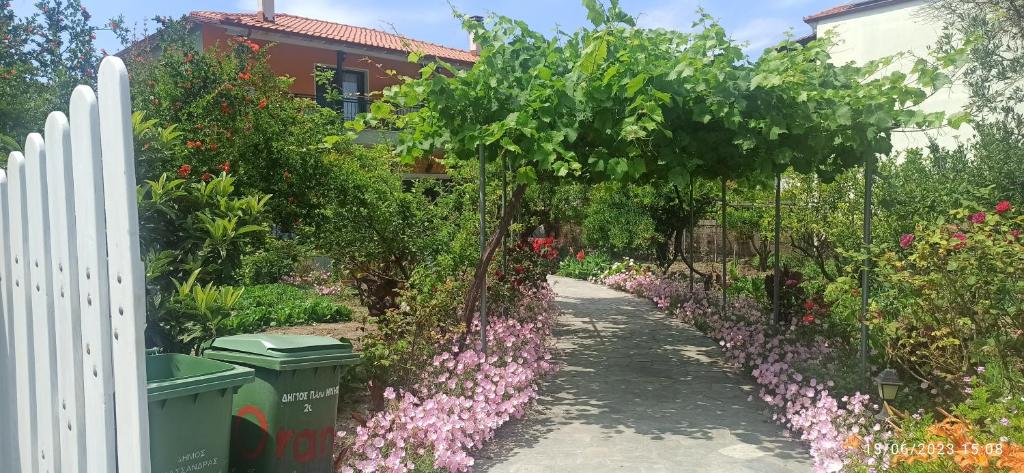 a garden with pink flowers and a white fence at Orange Tree Garden in Pefkochori