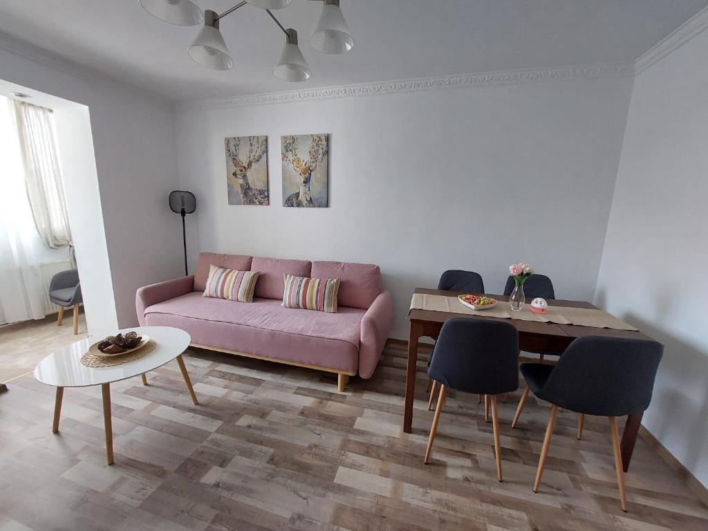 un soggiorno con divano rosa e tavolo di Hellen Studio Predeal a Predeal