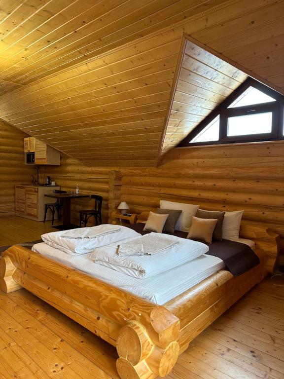 uma cama grande num quarto de madeira com uma janela em Батярський Двір em Pasiky-Zubryts'ki