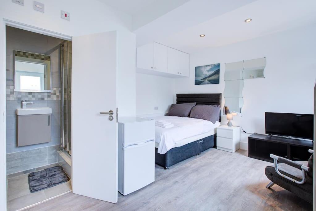 ein weißes Schlafzimmer mit einem Bett und einem TV in der Unterkunft Comfy and Convenient Studio Suite Lewisham with Free street parking, WIFI and quick access to central London Sleep 3 in Forest Hill