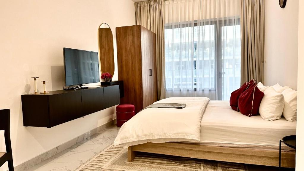 a bedroom with a large bed and a television at Cozy Studio In Masdar City in Al Qurayyah