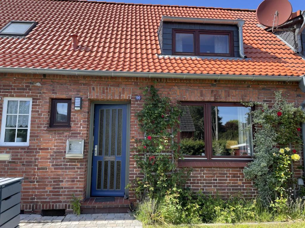 uma casa de tijolos com um telhado laranja e uma porta azul em Ferienhaus Jenny em Flensburg