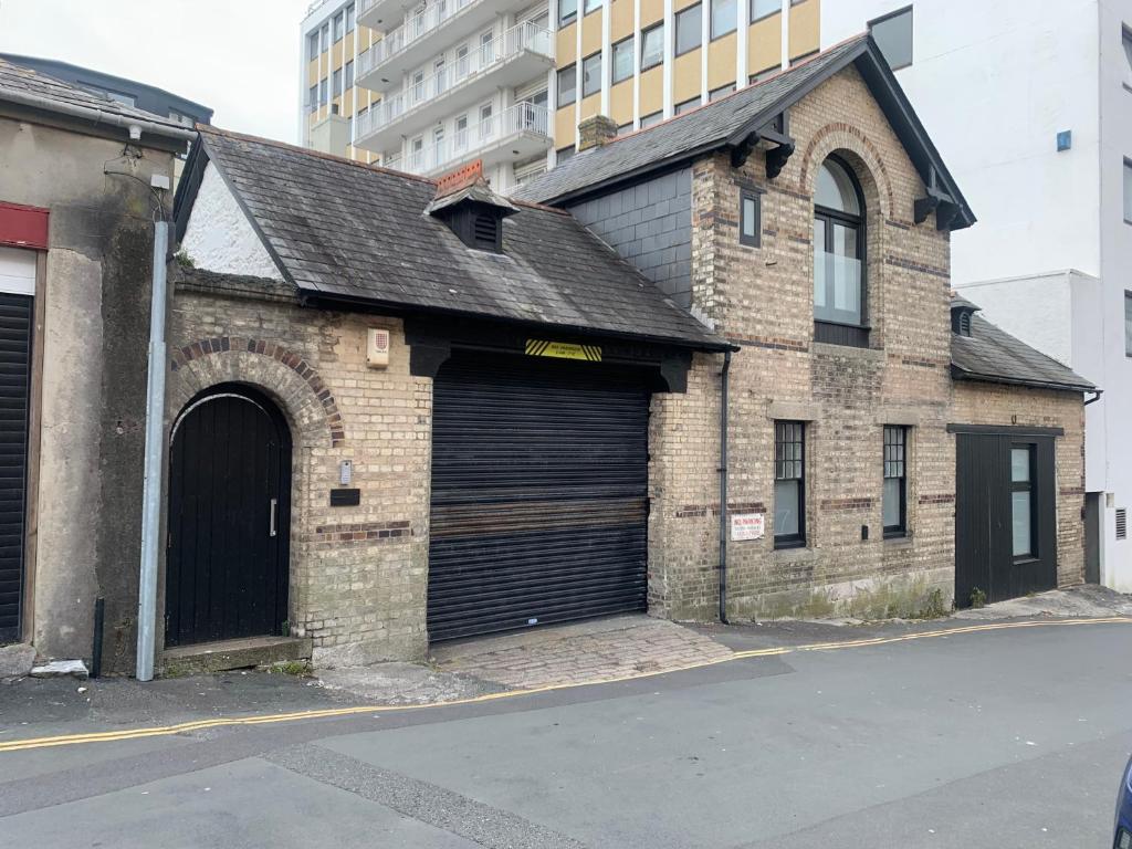 un antiguo edificio de ladrillo con dos grandes puertas de garaje en Executive Coach House on the Hoe 2 free parking spaces en Plymouth