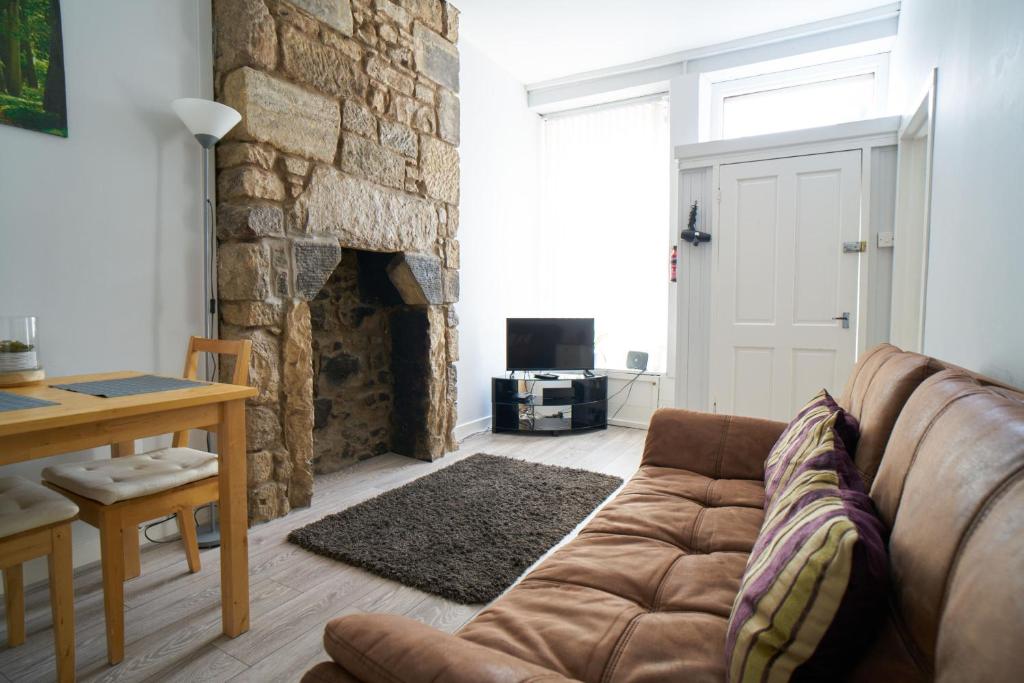 a living room with a couch and a stone fireplace at Douglas Gatehouse in Douglas