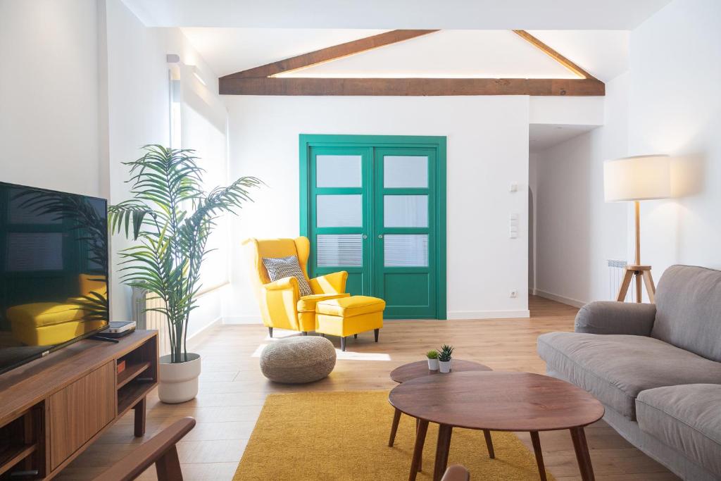 El Retiro de San Francisco - Piso de diseño - 4-5 plazas في أوفِييذو: غرفة معيشة فيها باب أخضر وكراسي صفراء