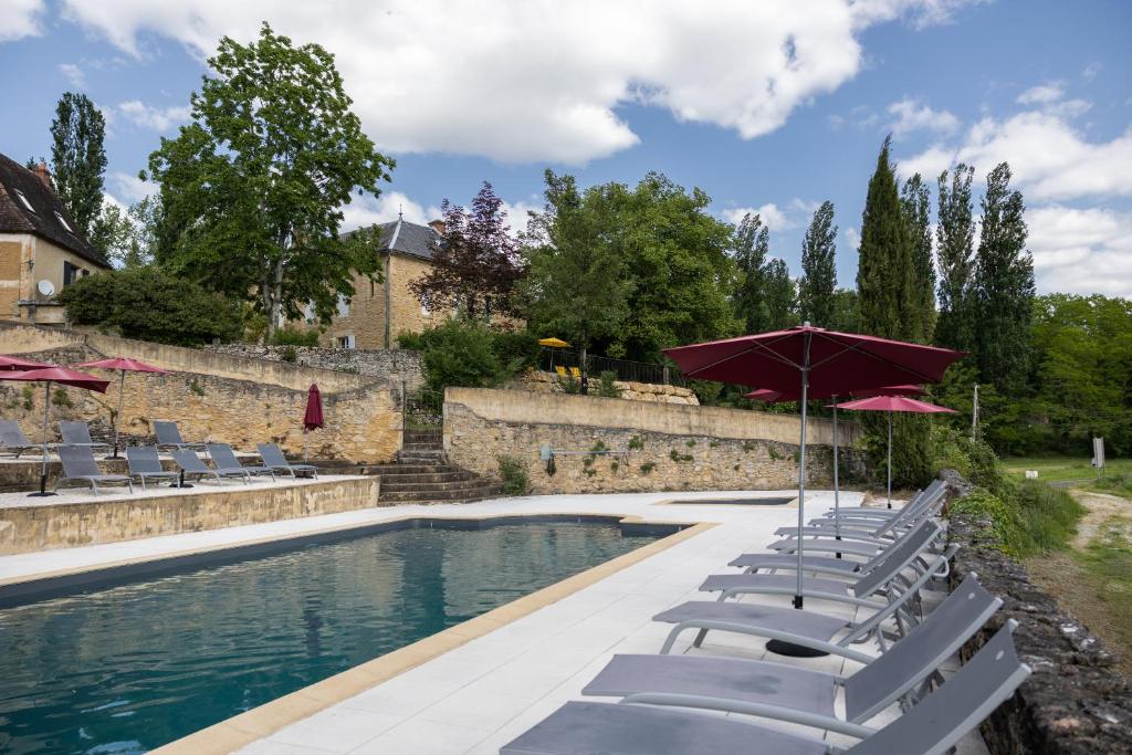 einen Pool mit Liegestühlen und einem Sonnenschirm in der Unterkunft Domaine Les Maurelles in Milhac