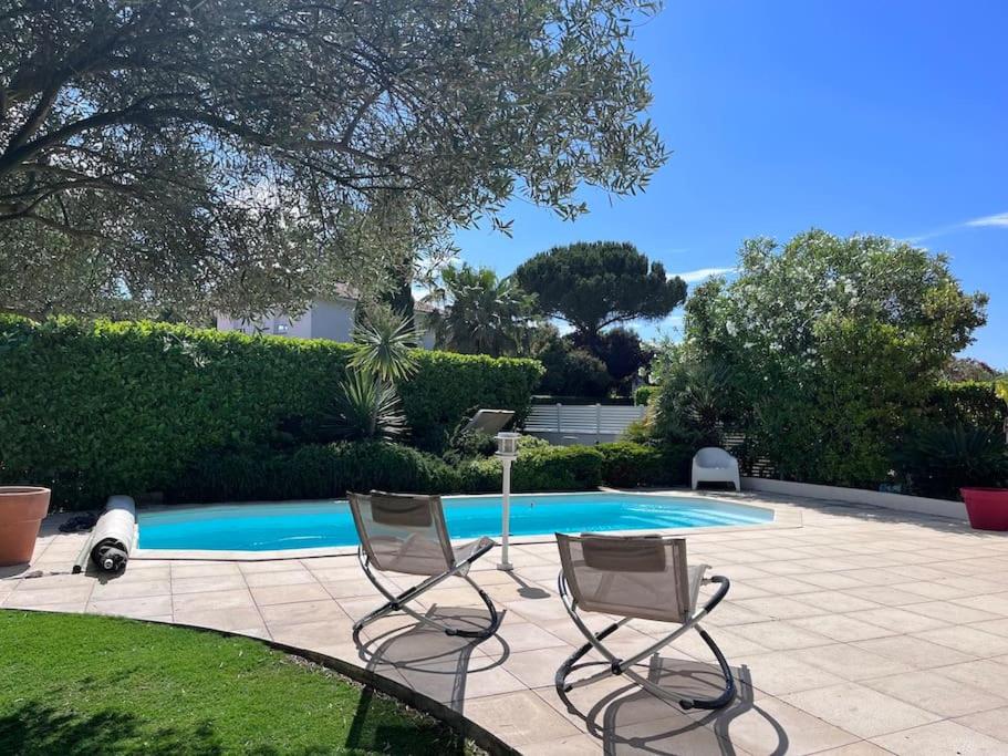 un patio avec deux chaises et une piscine dans l'établissement Villa avec piscine domaine du Golf, à Baillargues