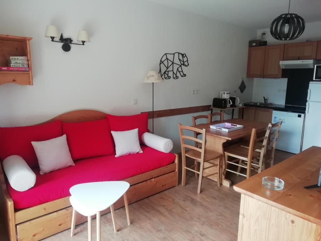 un soggiorno con divano rosso e una cucina di Orcières Appartement au pied des pistes avec piscine a Orcières
