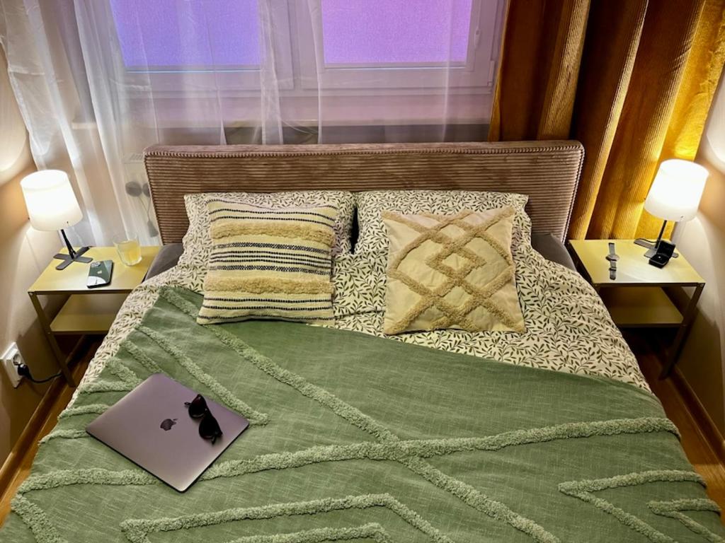 a bed with a green blanket and a laptop on it at Klimatyczne mieszkanie w centrum Giżycka in Giżycko