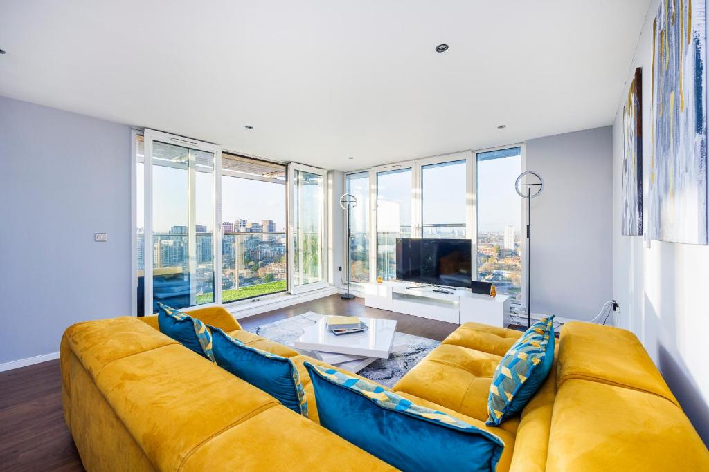 een woonkamer met een gele bank en grote ramen bij Austin David Apartments ExCeL in Londen