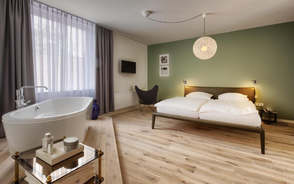 a bedroom with a bed and a bathtub and a bed and a tub at Das Eckert - Lifestyle Design Hotel & Fine Dining bei Basel (Grenzach) in Grenzach-Wyhlen