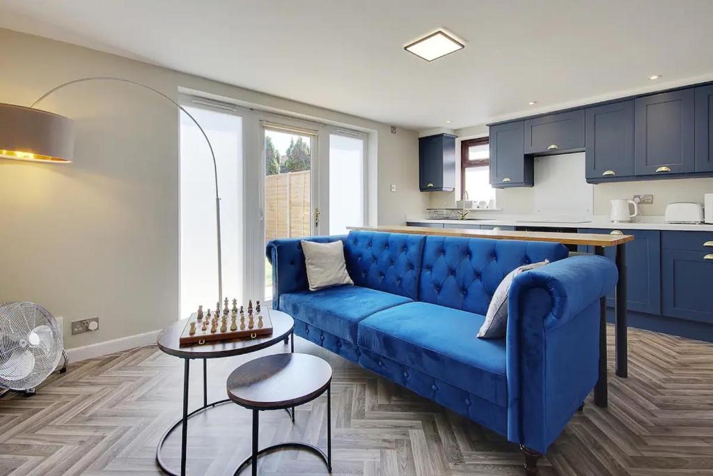 a living room with a blue couch and a kitchen at Windham Mews - Stunning Flat in Seaside Town in Bournemouth