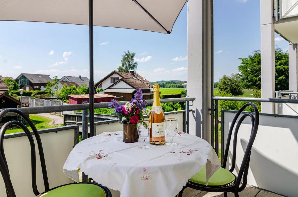a table with a bottle of wine and flowers on a balcony at Relaxen am Illmensee in Illmensee