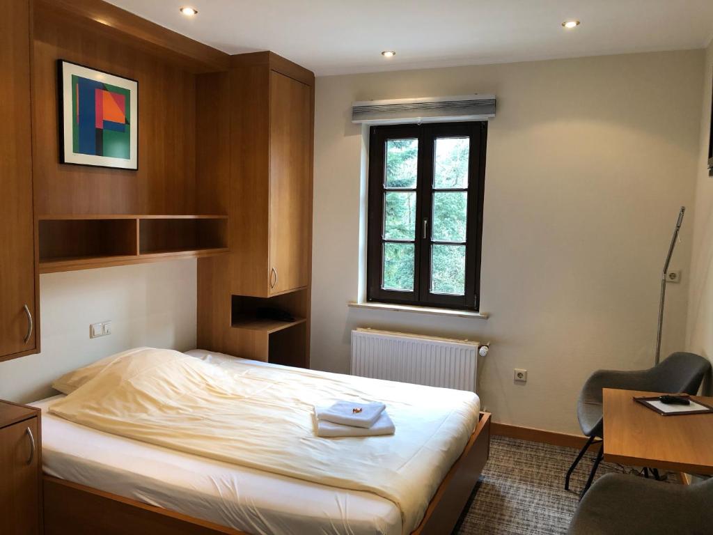 a bedroom with a bed and a desk and a window at Hotel Auberge Rustique in Beaufort