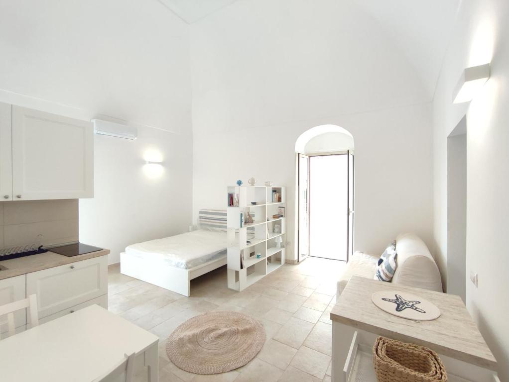 ein weißes Zimmer mit einem Bett und einem Tisch in der Unterkunft Elegante Monolocale + Soppalco in Centro e Vicino al Mare - DiscoverGargano Com in Vieste