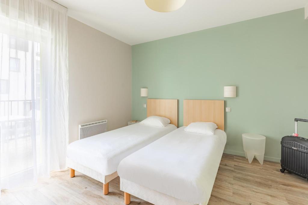 two white beds in a room with a window at Appart’City Confort Tours in Tours