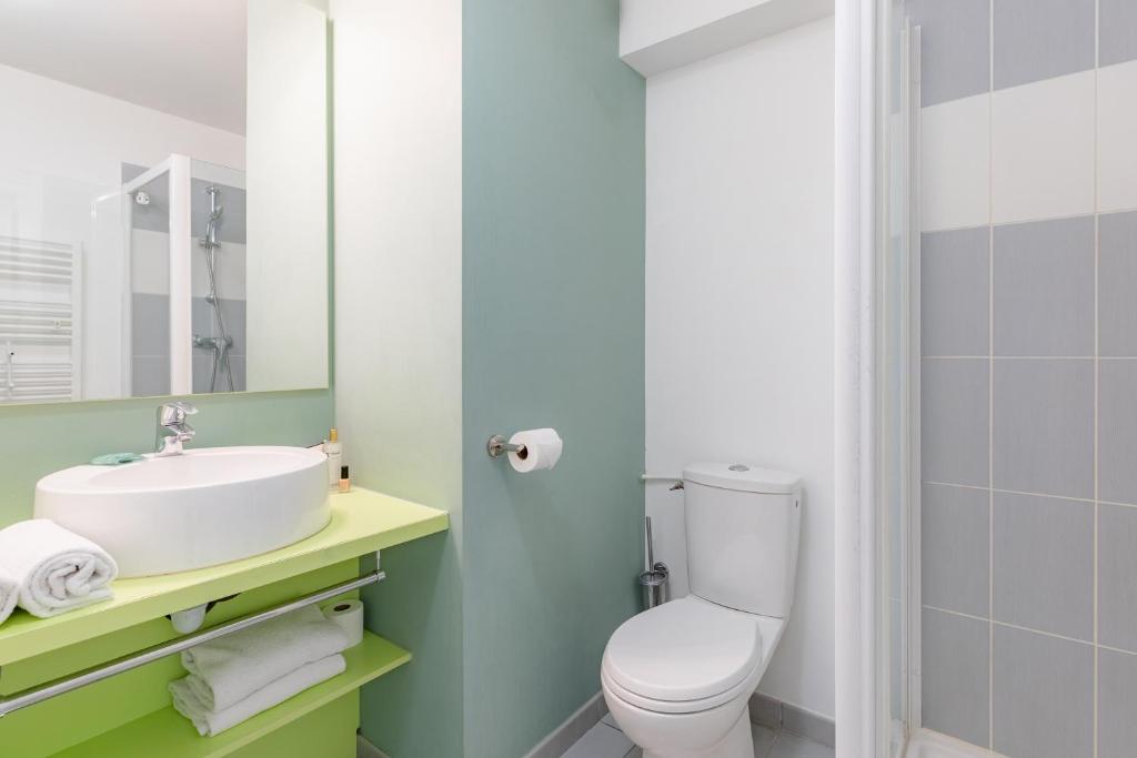 a bathroom with a white toilet and a sink at Appart’City Confort Tours in Tours